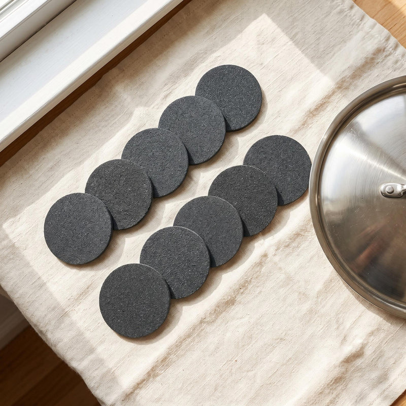 Ten Steelé Mini discs on a linen towel beside a stainless steel lid